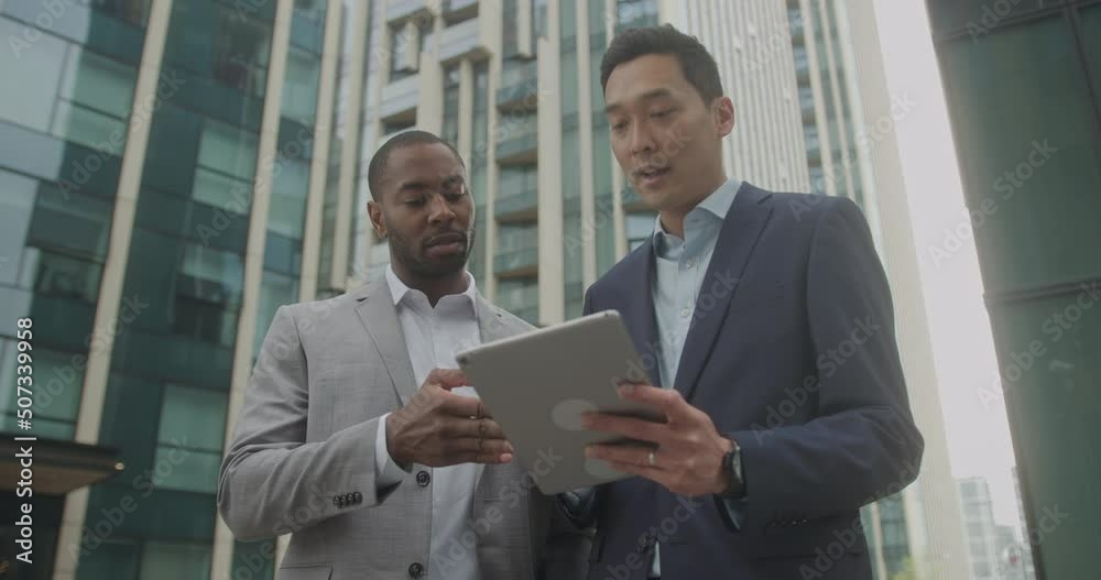 Business Men Meeting Outdoors using Digital tablet Technology on Street Business Men Meeting Outdoors using Digital tablet Technology on Street