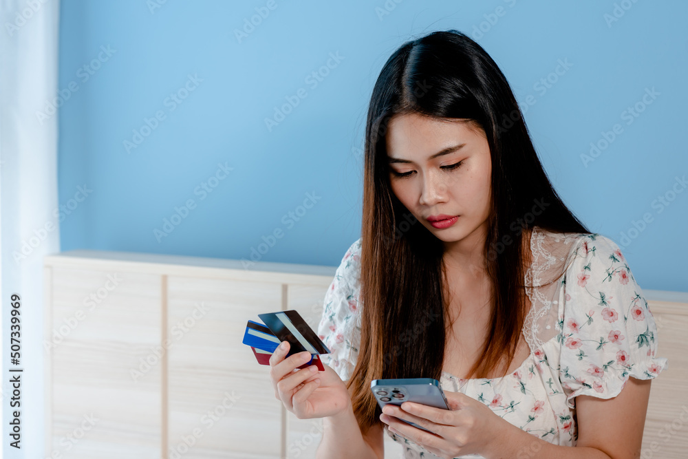 Close-up of a beautiful long-haired Asian girl's face, holding a credit card up to look at it, with a face was stunned and looked at the credit card like that.