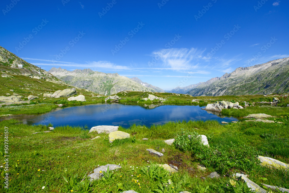 Beautiful landscape panorama by the lake with mountains in the background. Photograph was taken at a mountain pass in Switzerland in Swiss Alps. Beautiful landscape panorama by the lake with mountains in the background. Photograph was taken at a mountain pass in Switzerland in Swiss Alps.