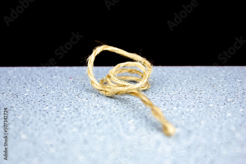 Winding the rope around your finger.Small rope.Strong thin thread rope on a black background close-up.