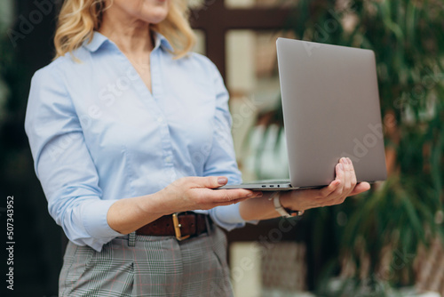 Close up hands of business woman holding and using laptop, standing outdoors