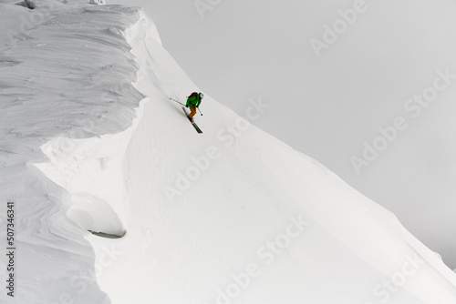 Man splitboard freerider skilfully rides down from top of ridge. Ski touring in mountains. photo