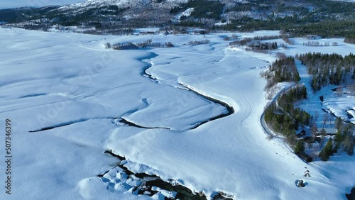 Scenic aerial video of winter creek in Norway's snowy mountains. Rossvatnet lake, Hattfjelldal municipality in Nordland county. photo