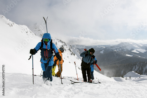Active people climbing snowy hill on mountain on skis and splitboards