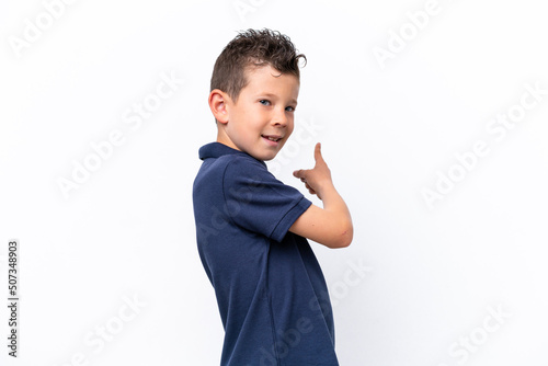 Little caucasian boy isolated on white background pointing back