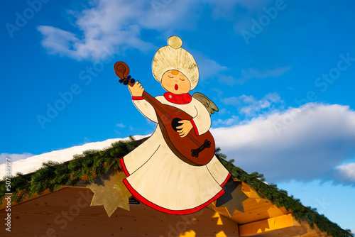 Christmas angel on a hut playing mandolin. Background blue sky and clouds
