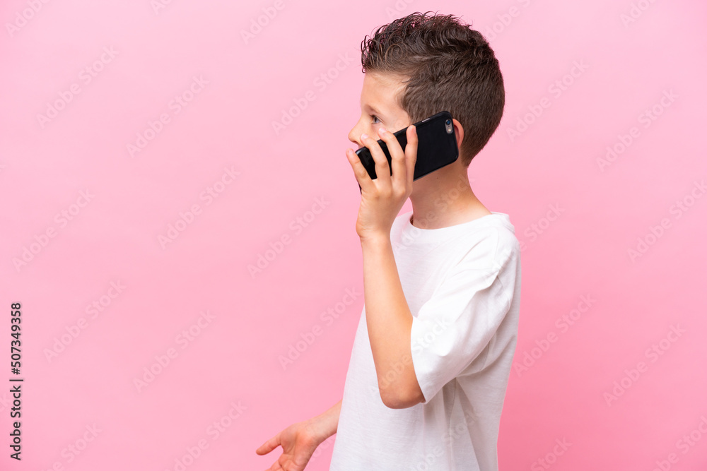 Little caucasian boy isolated on pink background keeping a conversation with the mobile phone with someone Little caucasian boy isolated on pink background keeping a conversation with the mobile phone with someone