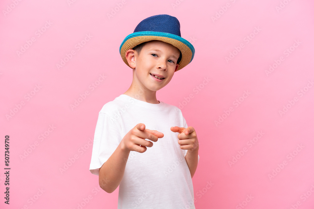 Little caucasian boy wearing a hat isolated on pink background points finger at you with a confident expression Little caucasian boy wearing a hat isolated on pink background points finger at you with a confident expression
