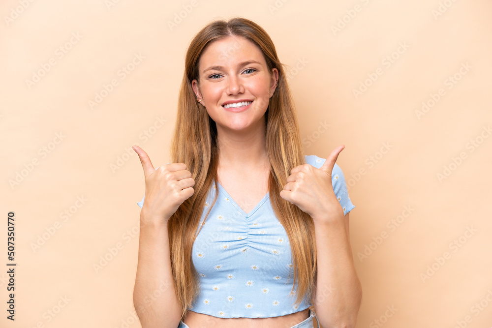 Young caucasian woman isolated on beige background with thumbs up gesture and smiling Young caucasian woman isolated on beige background with thumbs up gesture and smiling