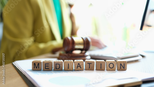 Mediator sitting near gavel of judge and words mediation closeup photo
