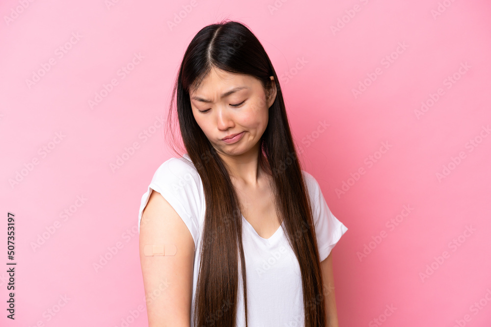 Young Chinese woman wearing a band aids isolated on pink background with sad expression Young Chinese woman wearing a band aids isolated on pink background with sad expression