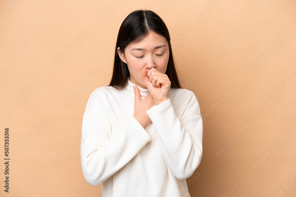 Young Chinese woman isolated on beige background coughing a lot Young Chinese woman isolated on beige background coughing a lot