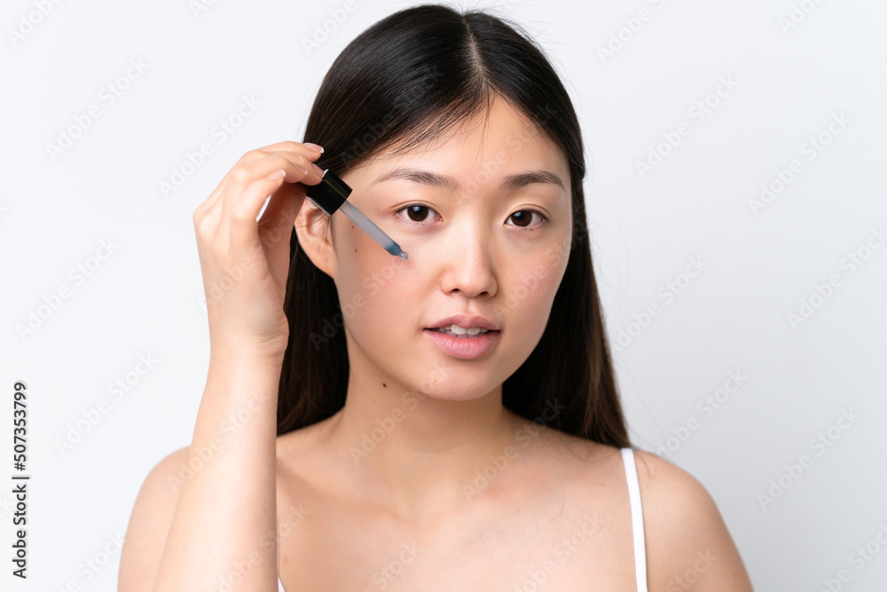 Young Chinese woman isolated on white background holding a serum. Close up portrait