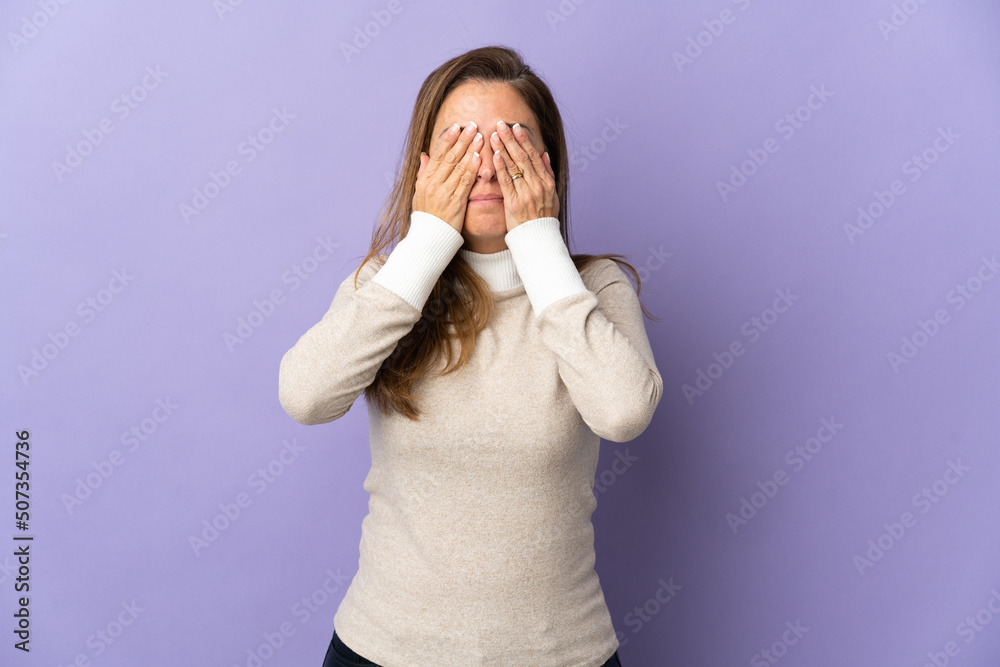 Middle age Brazilian woman isolated on purple background covering eyes by hands Middle age Brazilian woman isolated on purple background covering eyes by hands