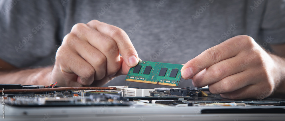 Technician installing random access memory on laptop computer. Technician installing random access memory on laptop computer.