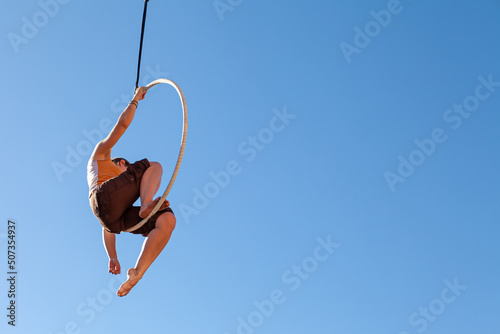a young trapeze artist suspended in mid-air attached to a circus hoop 