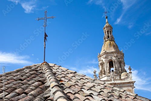 the bell tower of a medieval church as seen from a roof of old ceramic tiles