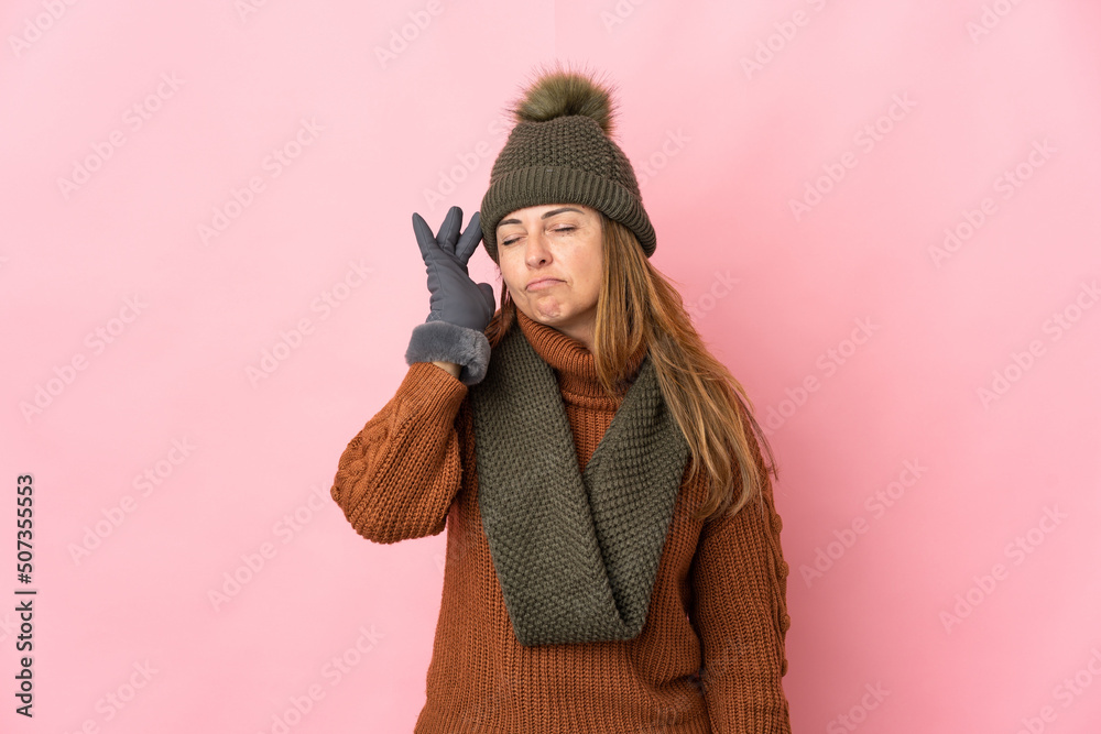 Middle age woman with winter hat isolated on pink background with headache Middle age woman with winter hat isolated on pink background with headache