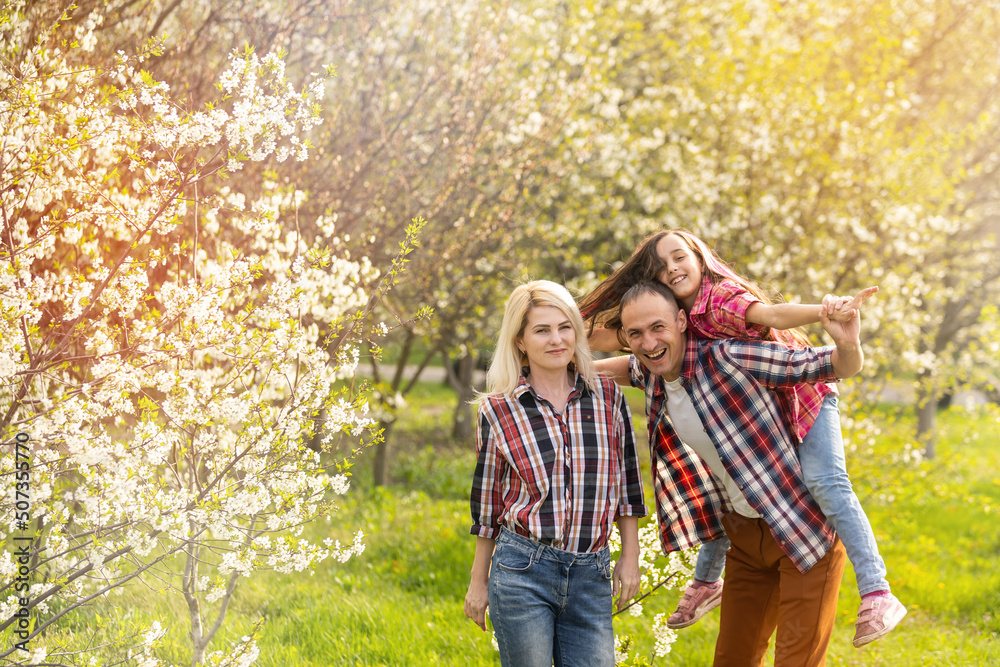 Fototapeta premium Happy family spending good time together in spring in a flowering garden
