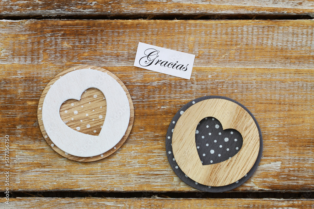 Gracias (thank you in Spanish) card with two wooden hearts on rustic surface