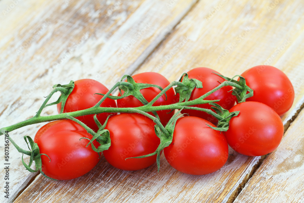 Delicious sweet cherry tomatoes on a stem on rustic wooden surface with copy space