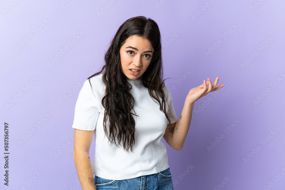 Young caucasian woman isolated on purple background making doubts gesture Young caucasian woman isolated on purple background making doubts gesture