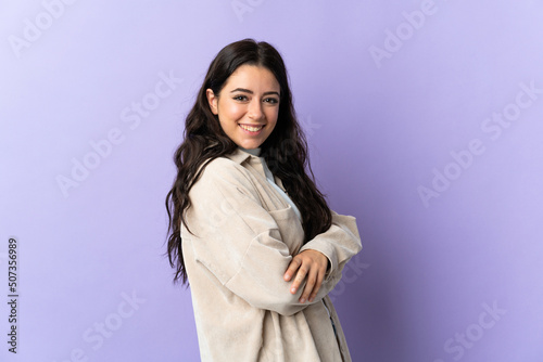 Young caucasian woman isolated on purple background with arms crossed and looking forward