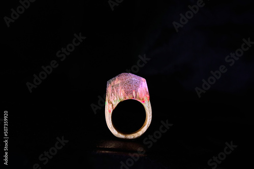  Photo of a wooden female ring on a white background. Epoxy resin is often used for decor and decorations. Eco-friendly material to create beautiful things. Bright unusual gift for a girl. 