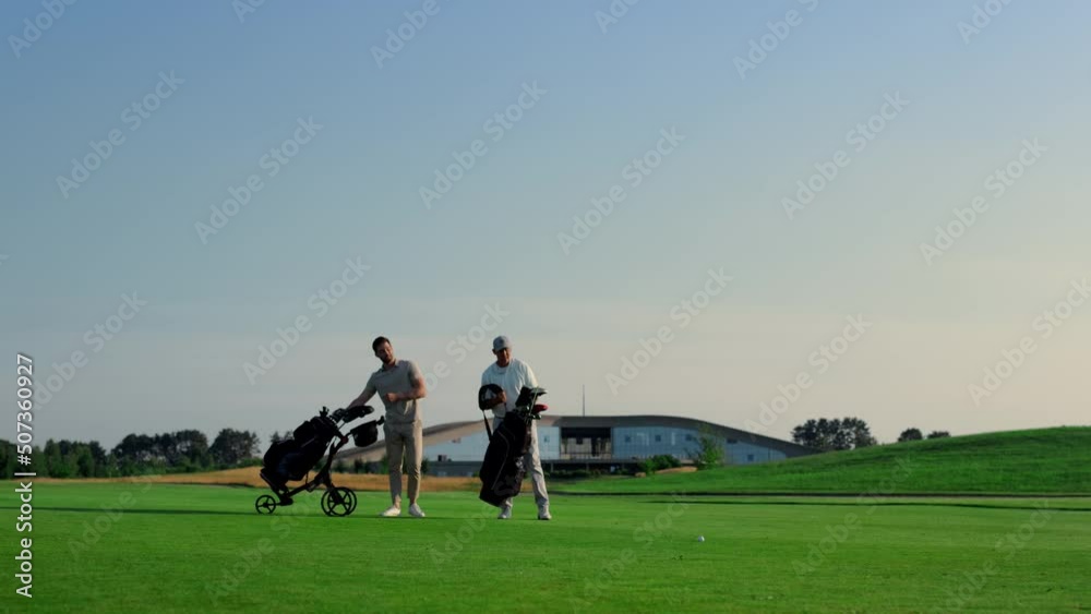 Golfers discuss course game competition outside. Two men choose putters on field Golfers discuss course game competition outside. Two men choose putters on field