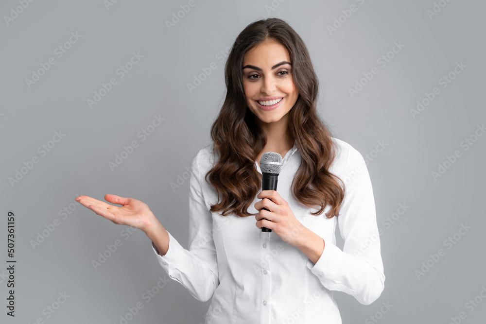 Young pretty woman singing a song with a microphone, presenting an event or having a party. Happy singing girl. Young pretty woman singing a song with a microphone, presenting an event or having a party. Happy singing girl.