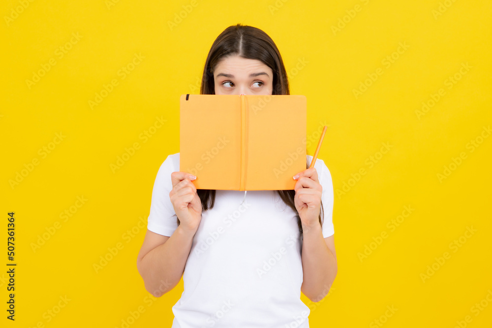 Female student holds books isolated on yellow background in studio. English language school, education concept. Female student holds books isolated on yellow background in studio. English language school, education concept.