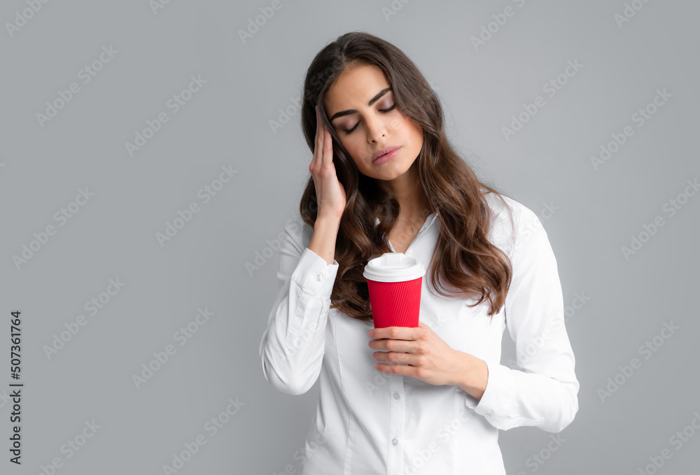 Portrait of a tired sleepy curly brunette woman holding takeaway coffee cup isolated over gray background. Portrait of a tired sleepy curly brunette woman holding takeaway coffee cup isolated over gray background.