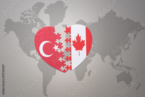 puzzle heart with the national flag of turkey and canada on a world map background. Concept.