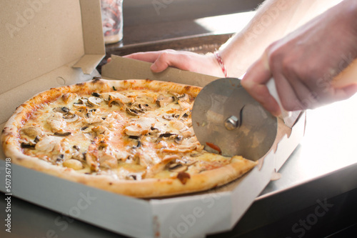 Cutting to cook a pizza in a box in the window.