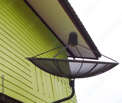 Dish antenna for receiving radio waves via satellite with home in countryside photo