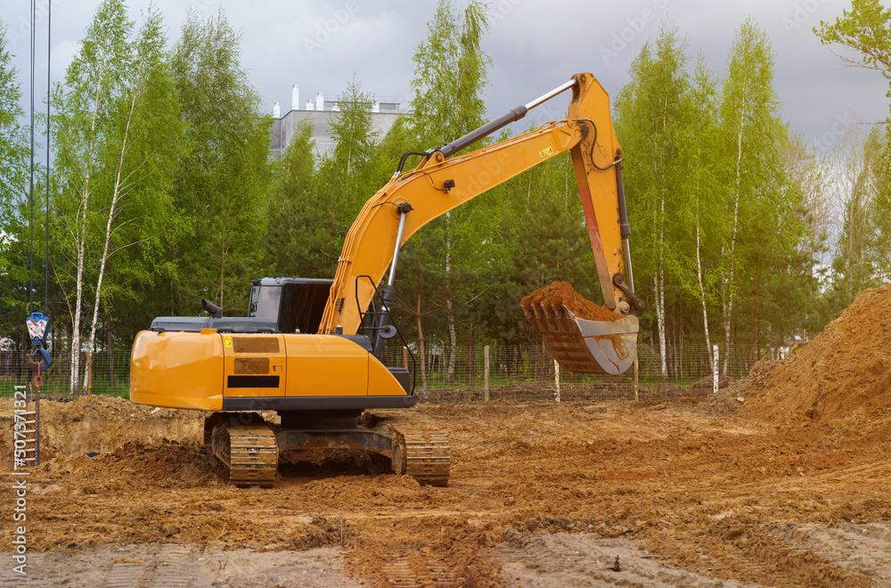 An excavator is digging a pit for a house. An excavator is digging a pit for a house.