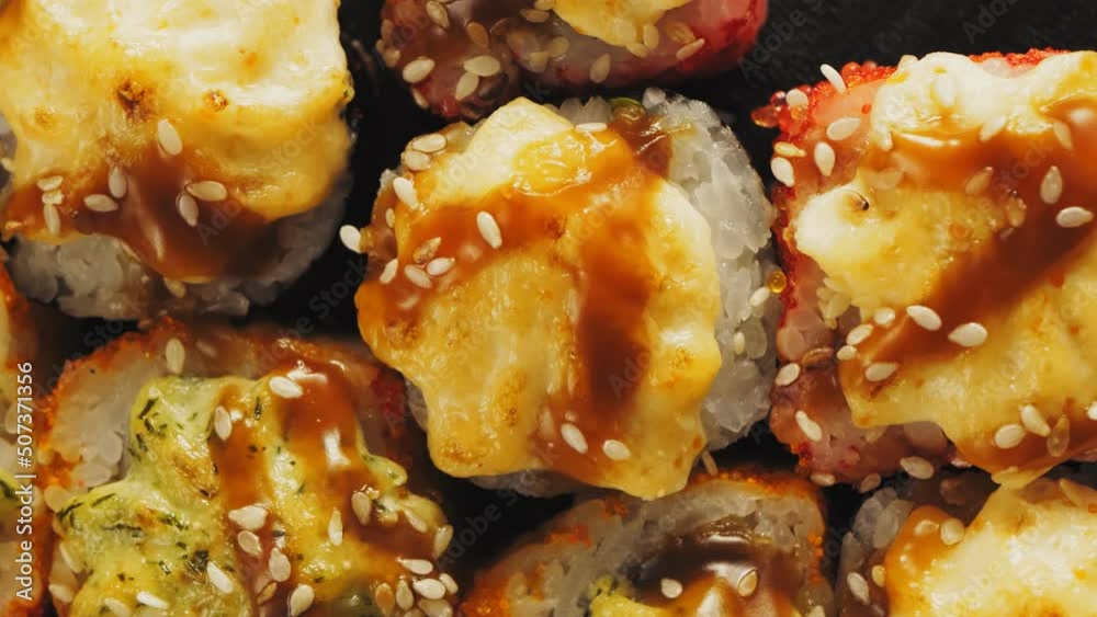 Baked rolls with crab in teriyaki sauce with sesame seeds on a black board close-up Baked rolls with crab in teriyaki sauce with sesame seeds on a black board close-up