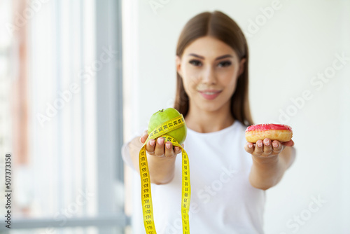 Beautiful young woman choosing between healthy food and junk food.