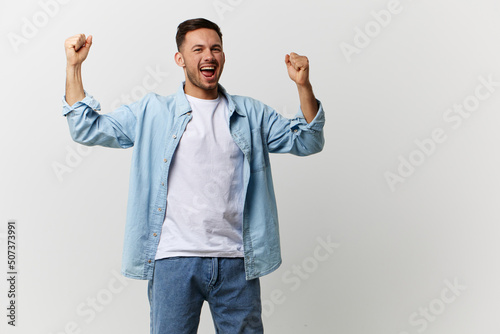 Lucky overjoyed tanned handsome man in casual basic t-shirt raise fists up posing isolated on over white studio background. Copy space Banner Mockup. Lifestyle People emotions Lottery winner concept