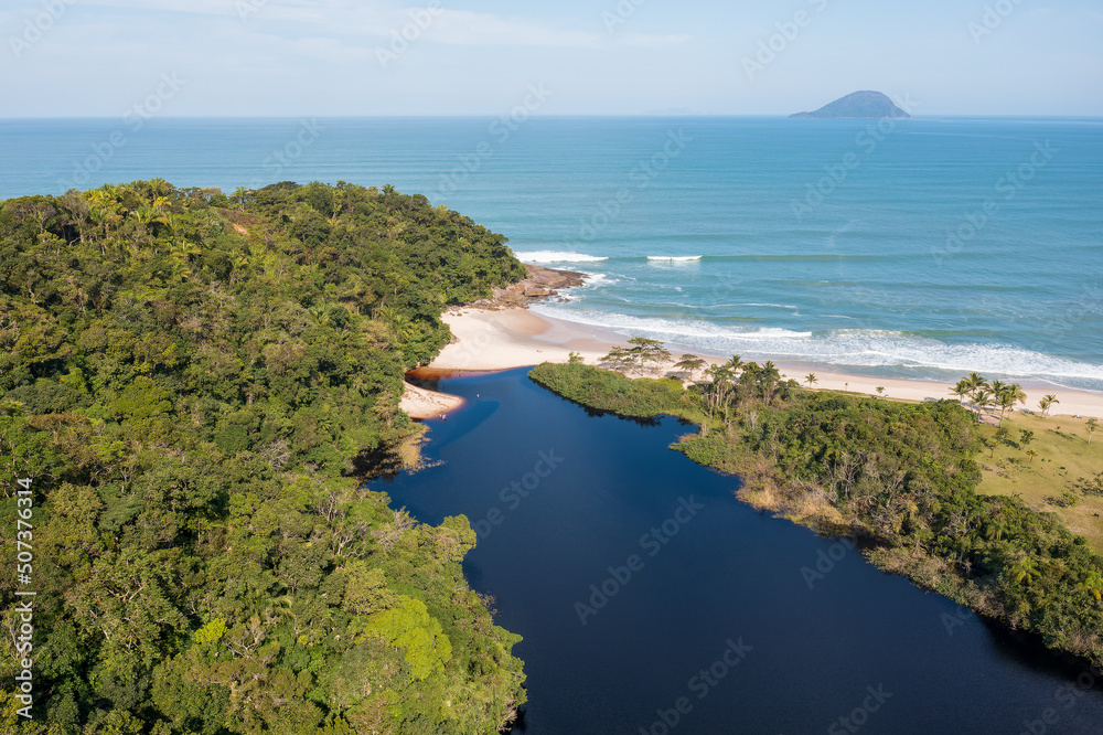 Vista aérea de uma linda praia do litoral paulista com areia clara, mar, costa e um rio