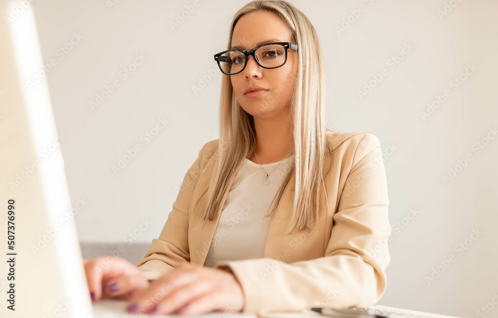 Business woman in office working on lap top. Business woman working from home concept. Beautiful young woman wearing glasses working at her desk.