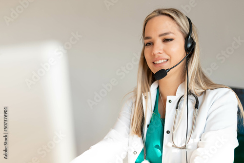 Smiling Attractive Young Woman Wearing Headset and stethoscope Near Her Computer Monitor. Health care customer support concept or ambulance dispatcher. 