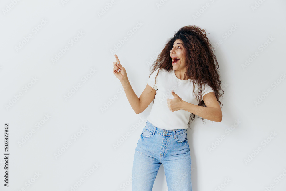 SEASONAL SALE OFFER. Cheerful, smiling curly Latin female stay near white wall, say Hey, Look at this, look up, show at free place copy space, cool ad for clothes sales. Studio shoot isolated SEASONAL SALE OFFER. Cheerful, smiling curly Latin female stay near white wall, say Hey, Look at this, look up, show at free place copy space, cool ad for clothes sales. Studio shoot isolated