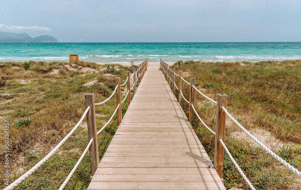 Wooden platform through the sand dunes leading to the beach of the sea