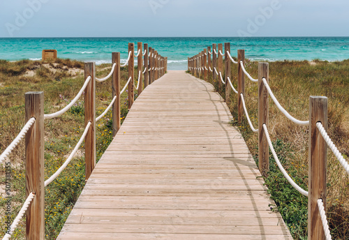 Wooden platform through the sand dunes leading to the beach of the sea © Nataliya Schmidt