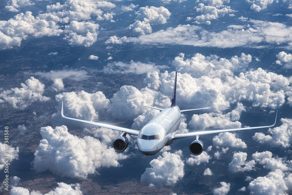 Airplane is flying above the clouds at in summer. Landscape with passenger airplane, mountains, blue sky. Aircraft is taking off. Business travel. Commercial plane. Aerial view. Transport. Jet