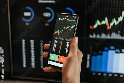 Financial trader man investor using mobile phone app to analyze cryptocurrency financial stock market