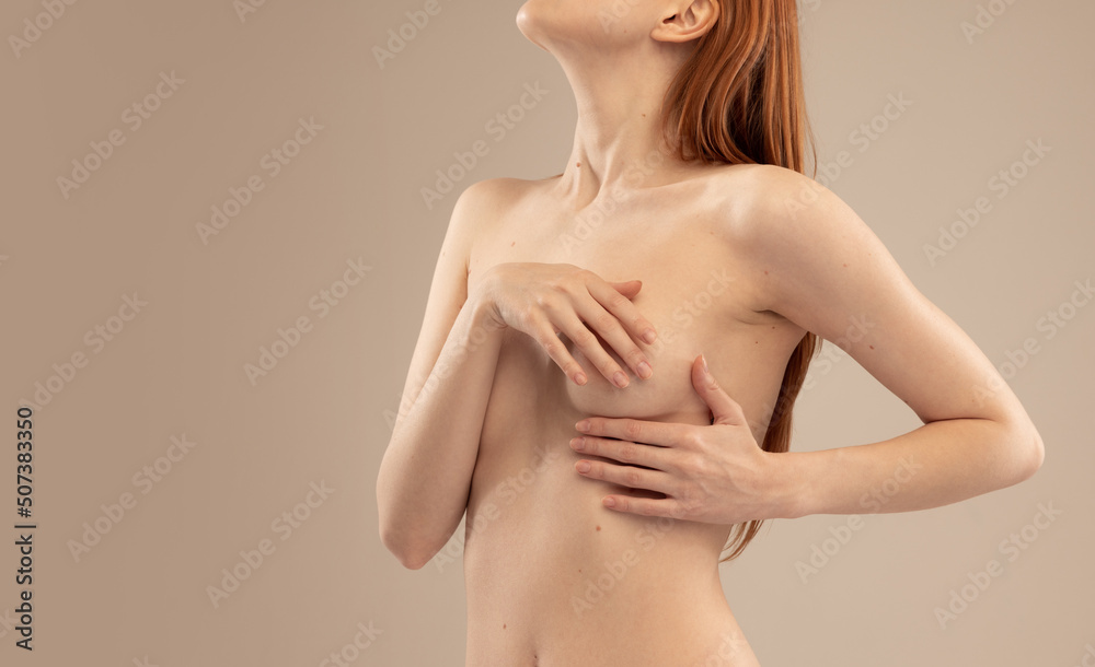 Cropped image of slim female body, breast isolated over beige studio background. Mammoplasty Cropped image of slim female body, breast isolated over beige studio background. Mammoplasty