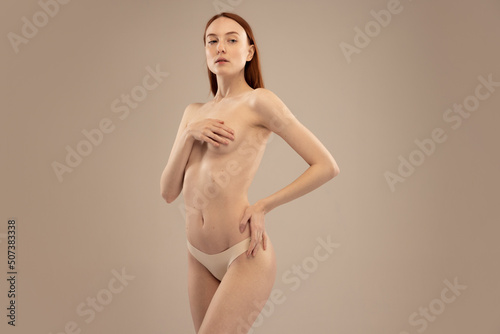 Cropped image of slim female body, breast isolated over beige studio background. Medical examination of women's health