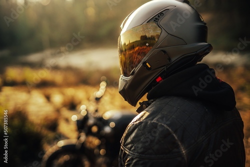 biker with helmet and leather jacket with his bike in the background photo